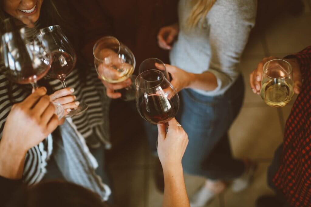 Five young ladies standing around with wine in their hands