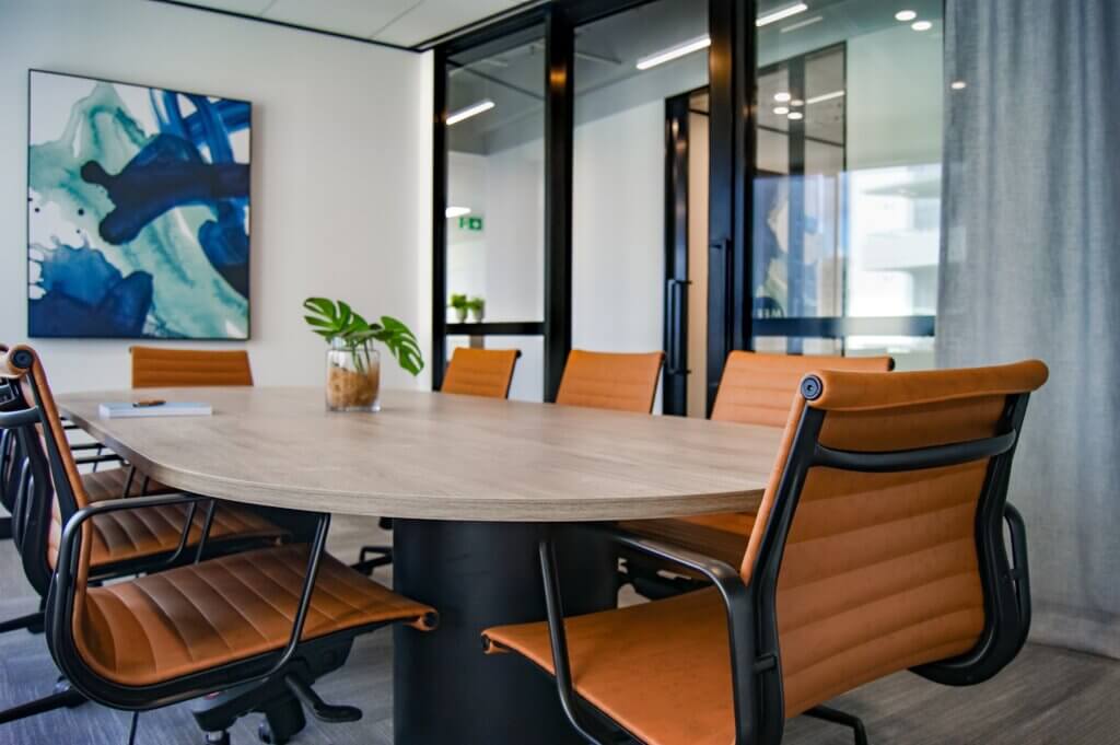 Desk with Orange Chairs, in Boardroom. With Covid-19 Policy document on the desk.