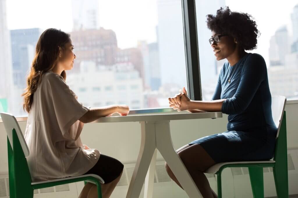 Two young women, sitting at a round table discussing work